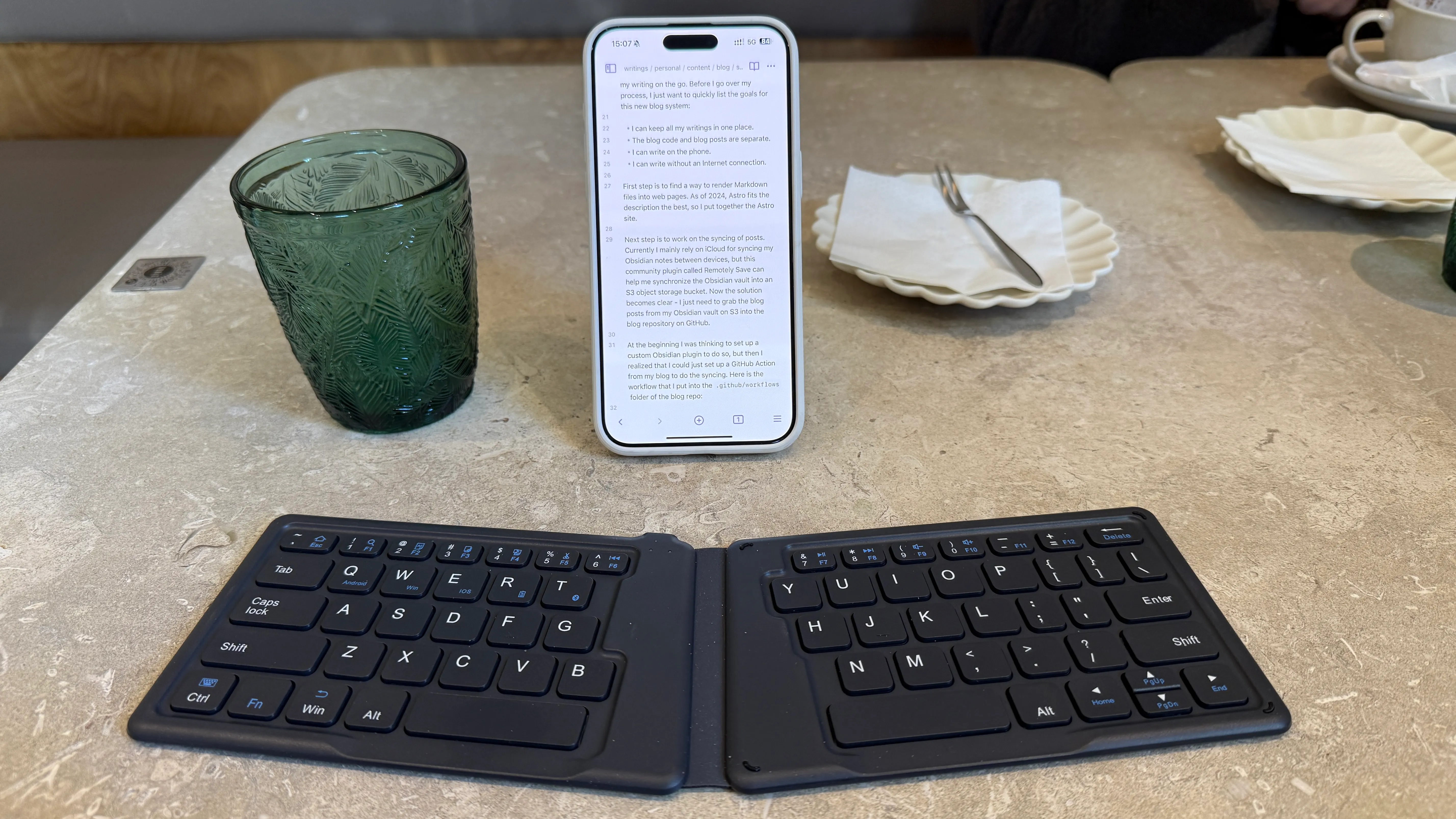 A picture of me writing using a foldable keyboard and a phone